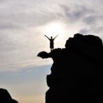 silhouette photography of person standing on rock